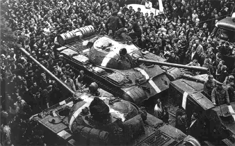 Einmarsch der Truppen des Warschauer Paktes in Prag im August 1968. Mehrere Panzer sind umringt von einer großen Menschenmenge, die gegen den Einmarsch demonstriert.