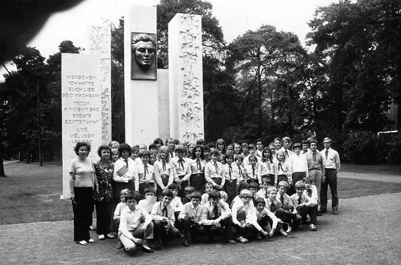 Prager Pioniere am Fučík-Denkmal im Bürgerpark Pankow, um 1974. Die Gruppe posiert mit ihren Betreuer:innen für ein Gruppenfoto vor dem Denkmal.