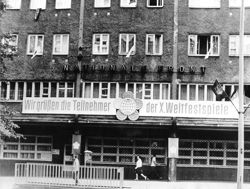 Für die 10. Weltfestspiele 1973 dekorierte Hausfassade in der Prenzlauer Allee. An der Fassade ist ein Schild angebracht, auf dem steht: „Wir grüßen die Teilnehmer der 10. Weltfestspiele.“
